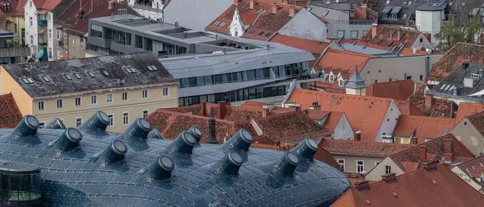 Das Bild zeigt die roten Dächer in der Innenstadt. Links unten sticht die Glasblase des Kunsthauses hinaus