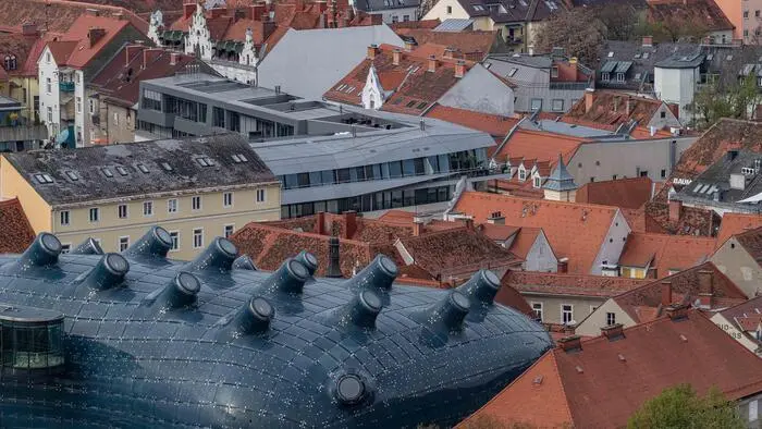 Das Bild zeigt die roten Dächer in der Innenstadt. Links unten sticht die Glasblase des Kunsthauses hinaus