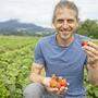 Daniel Dörfler mit einer Handvoll Bio-Erdbeeren.