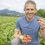 Daniel Dörfler mit einer Handvoll Bio-Erdbeeren.