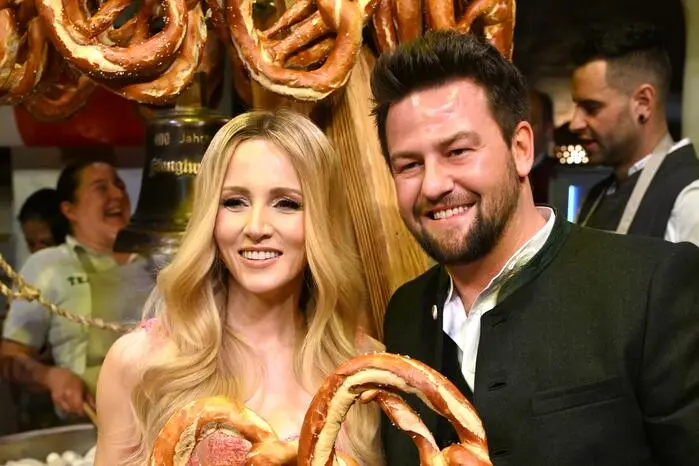Schlagerikone Melissa Naschenweng zeigt sich neben Stanglwirt-Gastronomiechef Johannes Hauser von den Riesenbrezen begeistert
