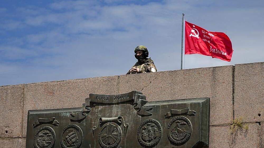 Ein russischer Soldat in Cherson, im Hintergrund eine sowjetisch angelehnte Fahne