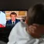 French President Emmanuel Macron is seen on a TV screen in