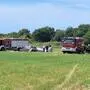 Man sieht zwei Feuerwehrwagen bei einem abgestürzten Flugzeug stehen