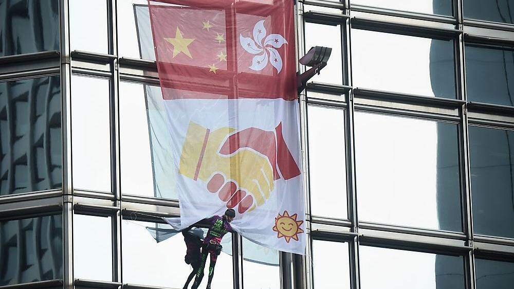 Robert entrollte ein Banner, das die Flaggen Chinas und Hongkongs sowie zwei sich schüttelnde Hände zeigt