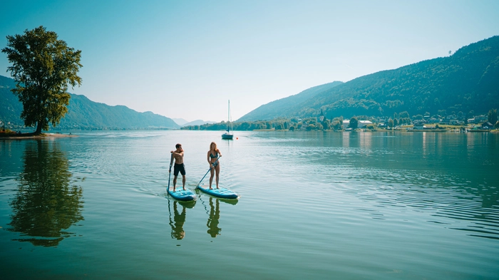 Zwei Stand-up-Paddler auf einem türkisen See.