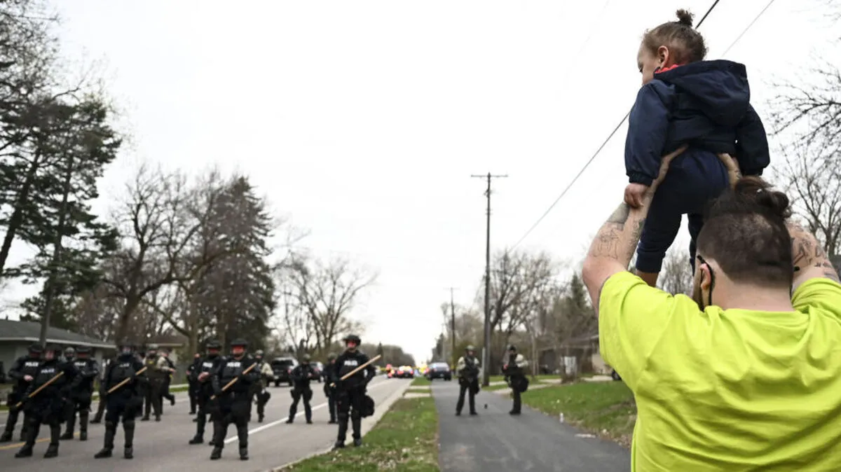 Der Bruder von Daunte Wright hält Wrights Sohn in die Höhe, als die Polizisten in Richtung Demonstranten marschieren