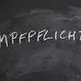 Impfpflicht translates as compulsory or mandatory vaccination in German language - text written in chalk on blackboard
