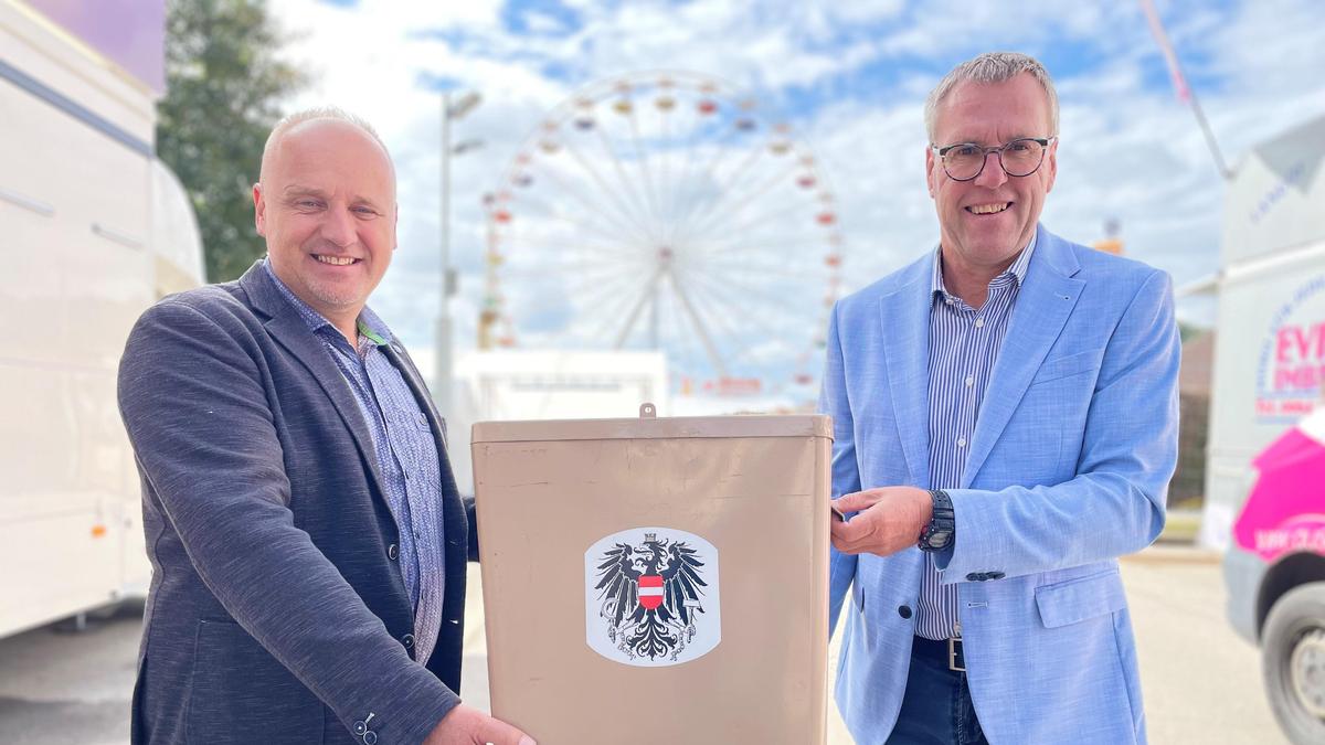 Wahlleiter Ernst Wölkart und Wahlschreiber Fritz Orasch (von links) aus St. Veit/Glan sitzen im Wahllokal mit Blick auf den Wiesenmarkt