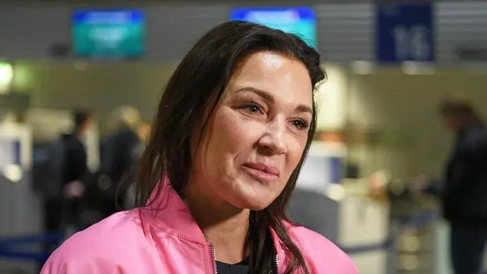 Simone Ballack auf dem Flughafen mit einer rosaroten Jacke