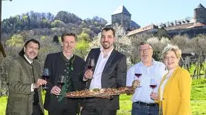 Auf dem Foto sieht man fünf Personen, die mit Weingläsern in der Hand in einem Weingarten vor der Burg Deutschlandsberg stehen und in die Kamera lächeln | Bürgermeister Josef Wallner, Weinbaudirektor Martin Palz, Winzer-Nachbar Norbert Hess und Evelyn Schweinzger (Geschäftsführerin Tourismusverband Südsteiermark) gratulierten Franz Josef Kollar (Mitte)