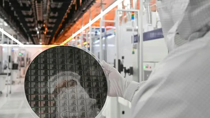 Ein Infineon-Mitarbeiter mit einem Galliumnitrid-Wafer im vollautomatisierten Reinraum der Chipfabrik in Villach