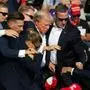 TOPSHOT - Republican candidate Donald Trump is seen with blood on his face surrounded by secret service agents as he is taken off the stage at a campaign event at Butler Farm Show Inc. in Butler, Pennsylvania, July 13, 2024. The suspected shooter who wounded Republican presidential candidate Donald Trump at a rally is dead, US media reported Saturday, along with one bystander. (Photo by Rebecca DROKE / AFP)