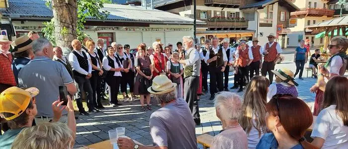 Viele Leute singen, andere hören zu auf dem Dorfplatz in Mallnitz