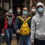 People wearing protective face masks cross a street in Hong Kong on February 9, 2020, as a preventative measure after a coronavirus outbreak which began in the Chinese city of Wuhan. - The previously unknown virus has caused alarm because of its similarity to SARS (Severe Acute Respiratory Syndrome), which killed hundreds across mainland China and Hong Kong in 2002-2003. (Photo by DALE DE LA REY / AFP)