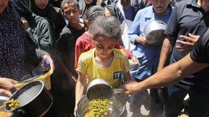 Palästinenser, die aufgrund der israelischen Angriffe von Rafah nach Deir al-Balah vertrieben wurden, warten in langen Schlangen auf Lebensmittel