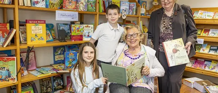 Zwei ältere Damen mit zwei Kindern in einer Bibliothek