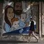 A man walks his dog past graffiti of Shiri and Yarden Bibas and their sons, Ariel, left, and Kfir, right, who were taken captive by Hamas, in Tel Aviv, Israel, Wednesday, Feb. 19, 2025. Yarden Bibas was freed from captivity earlier this month. (AP Photo/Oded Balilty)