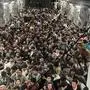 Die Internetseite „Defense One“ veröffentlichte am Montag ein Foto des vollgepackten Innenraums der Transportmaschine vom Typ C-17, in dem die Afghanen auf dem Boden sitzen - der vor lauter Menschen nicht mehr zu sehen ist.