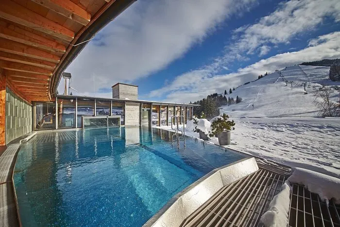 Naturnahes Wohnen – Holzhotel bei Salzburg.Wie der Name vermuten lässt, besteht das gesamte Holzhotel Forsthofalm aus Holz. Das aparte Wintersport-Domizil befindet sich im Salzburger Land und direkt an der Piste. Durch die Holzbauweise herrscht eine unnachahmliche Atmosphäre und Gäste haben das Gefühl, direkt in der Natur zu sein. Als Stärkung für die Piste trumpft das Holzhotel mit einem Bio-Frühstück auf inklusive einer großen Auswahl für Veganer. Zur Erholung wartet das Sky Spa mit ganzjährig beheiztem Rooftop-Pool und Sauna mit Bergblick.