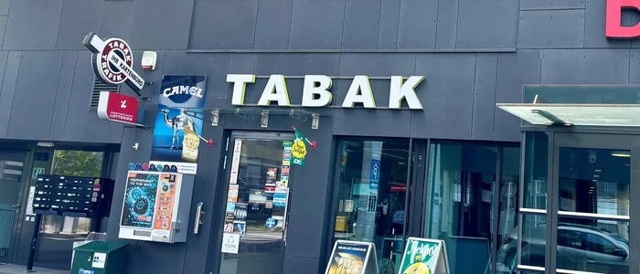 In einem Haus mit grauer Fassade ist eine Trafik untergebracht