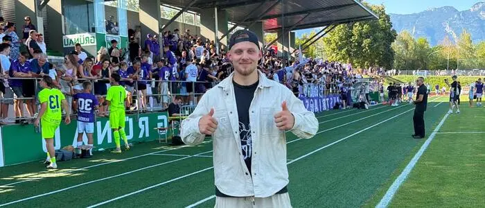 Ein Mann vor einem Spielfeld mit beiden Daumen nach oben