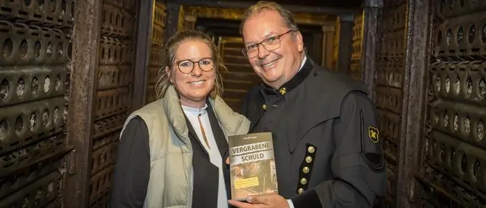 Ein Mann mit einem Buch neben einer Frau im Stollen eines Bergwerks