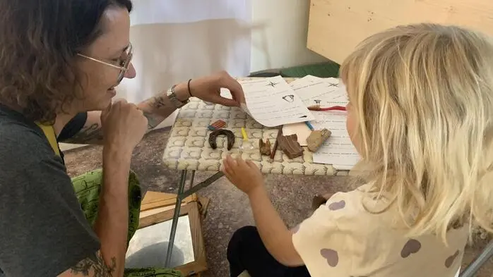 Eine Frau und ein Kind sitzen an einem Tisch auf dem Gegenstände liegen