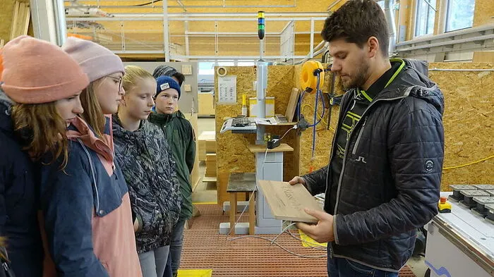 Werkstattleiter Fererberger zeigt, wie die hochmoderne CNC-Maschine in Windeseile Buchstaben ins Holz fräst 	