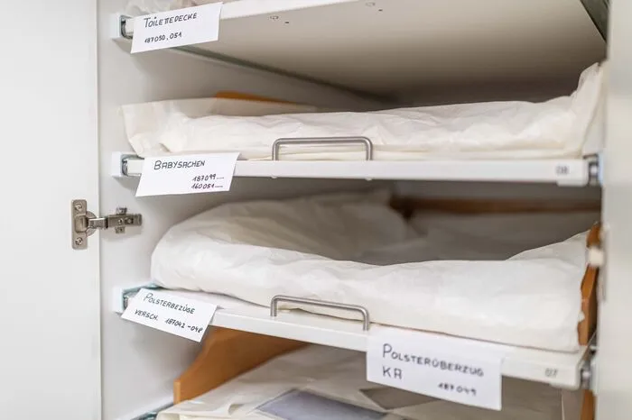 Die Tücher werden in Seidenpapier eingehüllt, um sie vor Staub und Abrieb zu schützen.