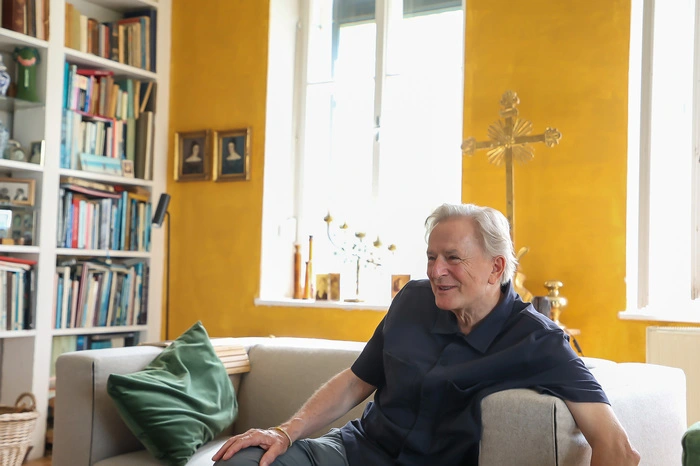 ... Die Schwestern wussten, dass wir evangelisch getauft sind und dass ich zum Atheisten wurde“, sagt der 68-Jährige – mit einem Kreuz wie ein goldener Widerspruch im Hintergrund.