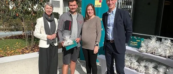 Zwei Frauen und zwei Männer stehen im Freien neben einem Tisch mit Geschenken und lächeln in die Kamera
