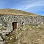 Ein grasbewachsener Berg mit einer alten Steinmauer, die in den Hügel eingelassen ist | Die Kaverne kurz unter dem Gipfel des Oisternigs war für die Unterbringung von Soldaten gedacht, kam jedoch nie zum Einsatz