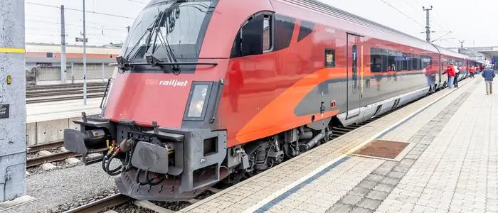 Ein roter ÖBB-Railjet steht an einem Bahnsteig