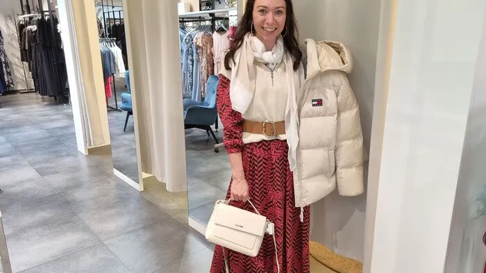 Ein gemustertes Kleid wird von Melanie Preßnitz mit einem Gürtel sowie einer hellen Steppjacke kombiniert