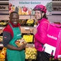 Zwei Männer; einer in Penny-Uniform, der andere im pinken Foodora Outfit | Der Discounter und das Lieferunternehmen expandieren gemeinsam