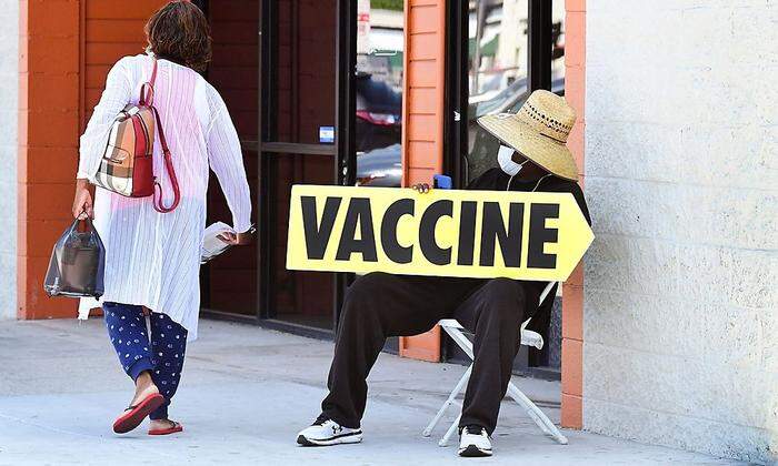 Am Crenshaw Boulevard in Los Angeles weist dieser Mann auf eine mobile Impfstelle hin.