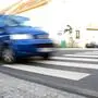 Ein blaues Auto nähert sich einem Zebrastreifen