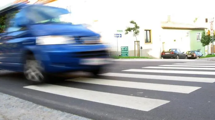 Ein blaues Auto nähert sich einem Zebrastreifen