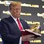 Republican presidential candidate former President Donald Trump holds gold Trump sneakers at Sneaker Con Philadelphia, an event popular among sneaker collectors, in Philadelphia, Saturday, Feb. 17, 2024. (AP Photo/Manuel Balce Ceneta)