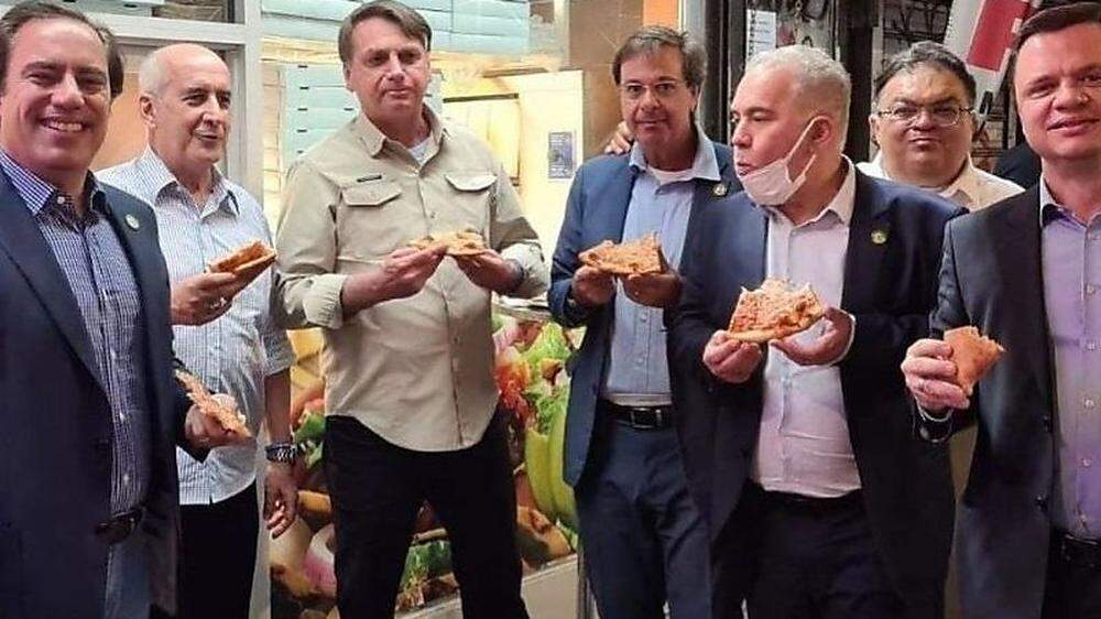 Brasiliens Präsident Jair Bolsonaro mit seiner Entourage beim Pizza-Essen auf dem Gehsteig