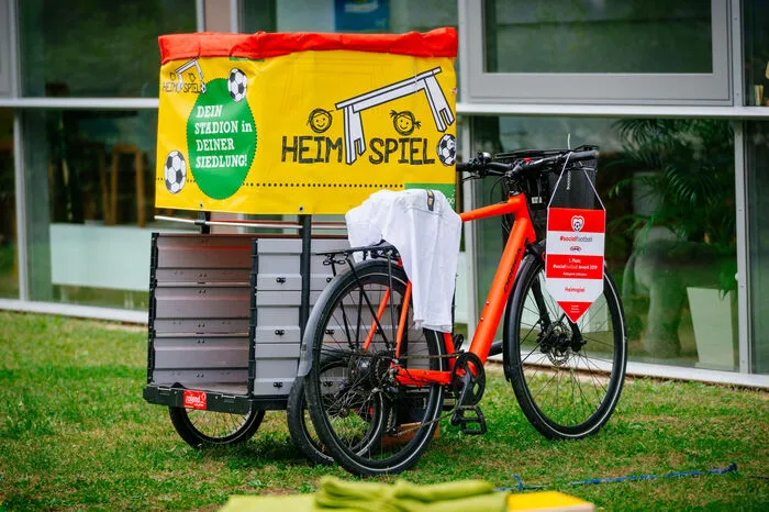 Ein ganzes Stadion hat dabei in zwei E-Bike-Anhängern Platz: Es besteht aus Bankerln und Bändern als Abgrenzung, die temporär, aber auch fix aufgebaut werden können