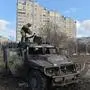An Ukrainian Territorial Defence fighter examines a destroyed Russian Armoured personnel carrier (APC) after the fight in Kharkiv on February 27, 2022. - Ukrainian forces secured full control of Kharkiv on February 27, 2022 following street fighting with Russian troops in the country's second biggest city, the local governor said. (Photo by Sergey BOBOK / AFP)