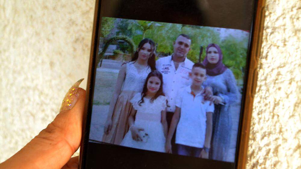 Eine Angehörige zeigt Fotos von Familienmitgliedern, die auf dem Schiff waren