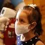 A girl wearing a mask has her body temperature checked while she arrives with her family at a beach side cafe in Gaza City, Monday, Oct. 12, 2020. The Hamas-run authorities allowed cafes and restaurants to reopen under strict regulations after a month and a half of closure as the coronavirus spread in the Gaza Strip. (AP Photo/Adel Hana)