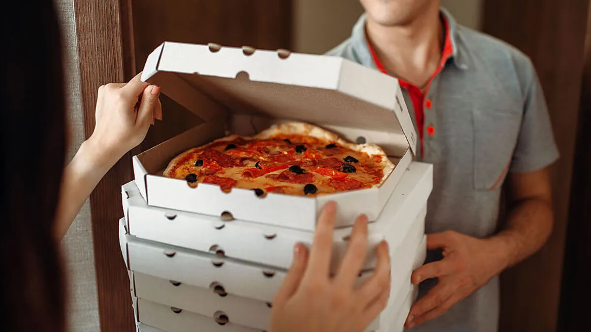Delivery man shows pizza to customer at the door