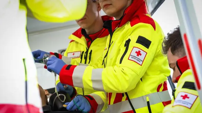 Mehrere Rotkreuz-Sanitäter stehen bei einem Patienten im Rettungswagen