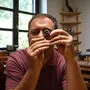Simon Ickinger blickt durch seine Lupe, um die filigranen Teile besser zu erkennen