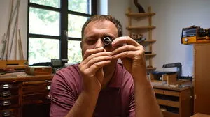 Simon Ickinger blickt durch seine Lupe, um die filigranen Teile besser zu erkennen