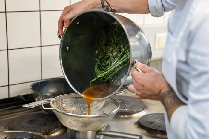 Der aufgekochte Brennnesselsud wird über ein Sieb abgeseiht